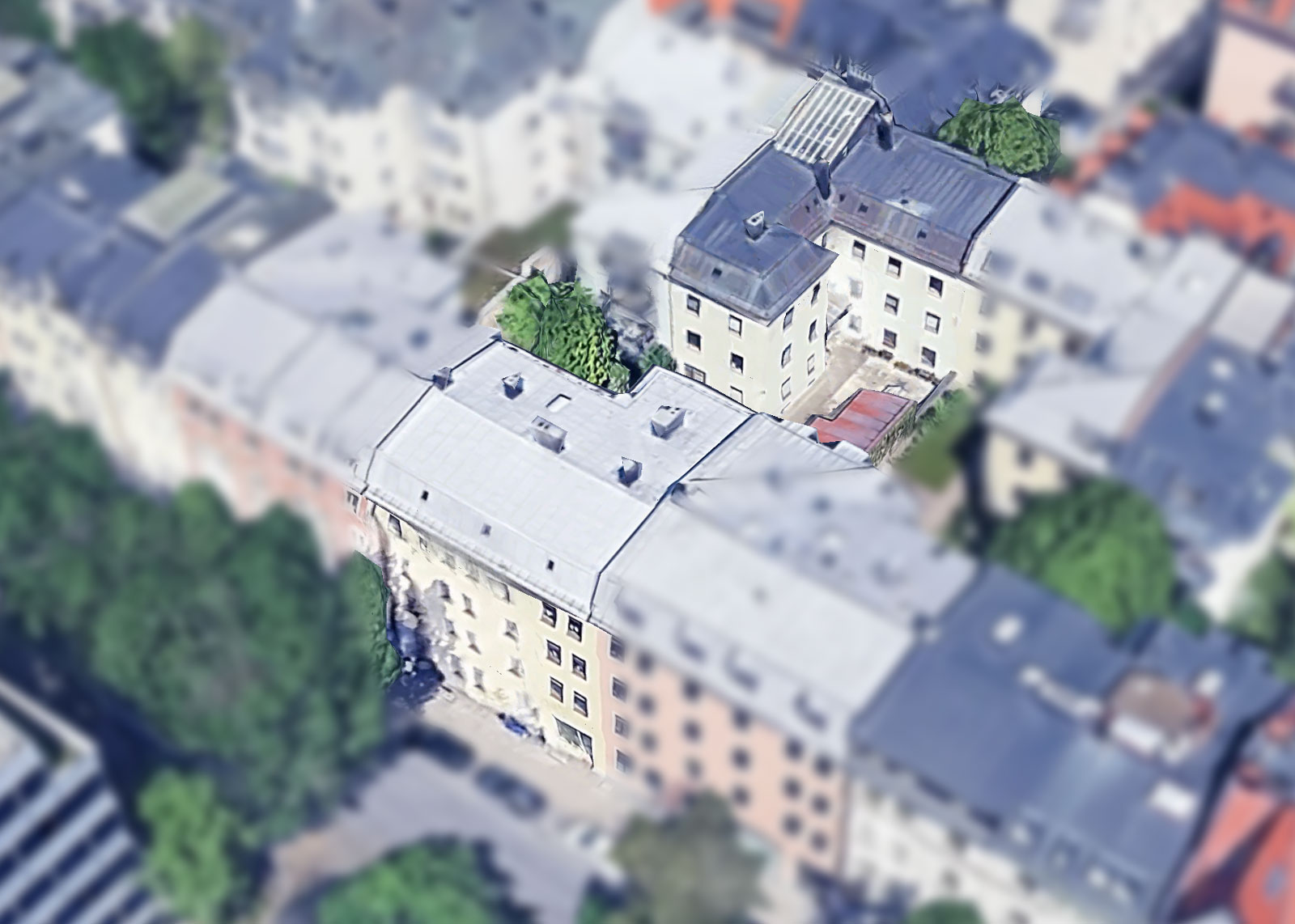 Luftaufnahme eines zentral gelegenen Münchner Mehrfamilienhauses mit charakteristischem Blechdach und Innenhof – Ansicht von oben für Projektvorstellung